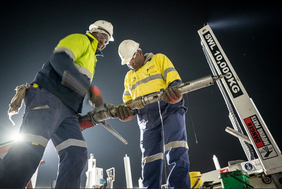 Crew handling drill rods at night